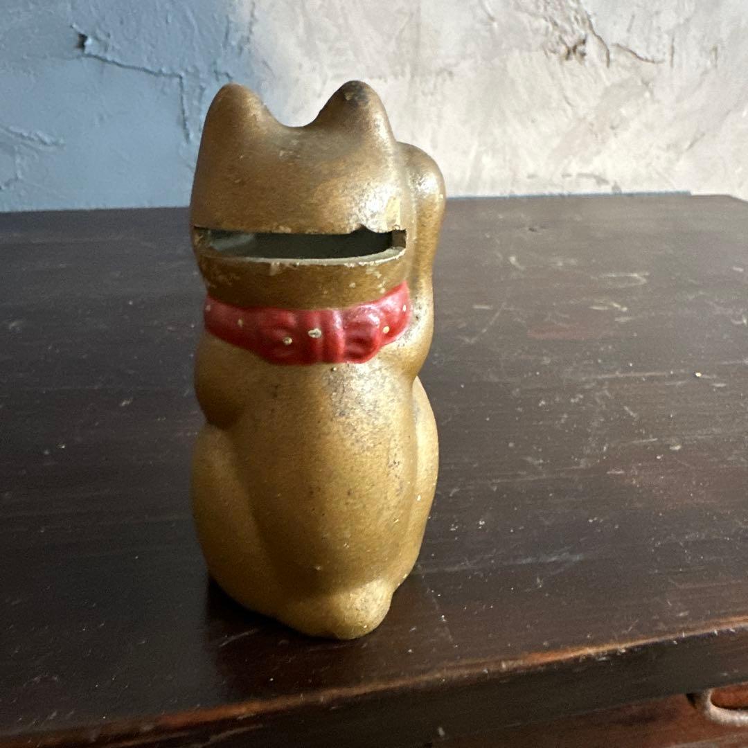 シュールなお顔の陶器製　金色の招き猫貯金箱